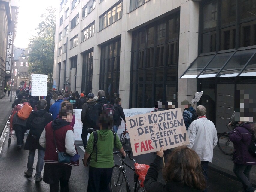Demonstrant*innen mit einem Pappschild: "Die Kosten der Krisen gerecht FAIRteilen"
