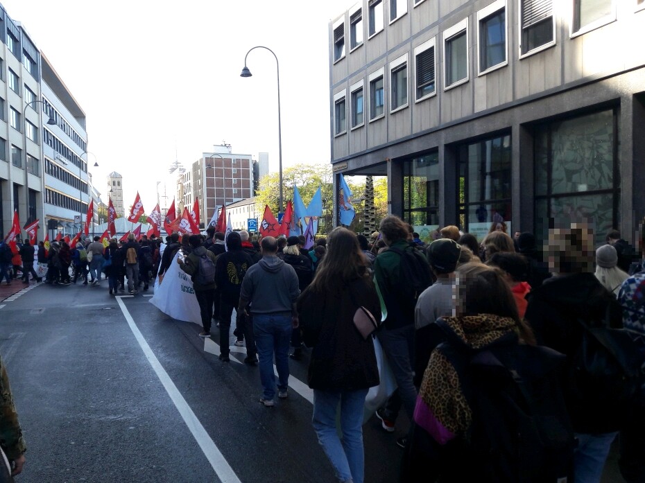 Demozug durchs Kölner Bankenviertel, im Hintergrund zahlreich rote Fahnen von marxistisch-leninistischen Organisationen.