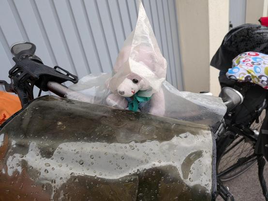 Pluche muis met regenjas op het stuur