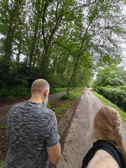 0.6 selfie of @regtur (left) and me (janneke, right) seen from behind, walking on a small road lined with trees.