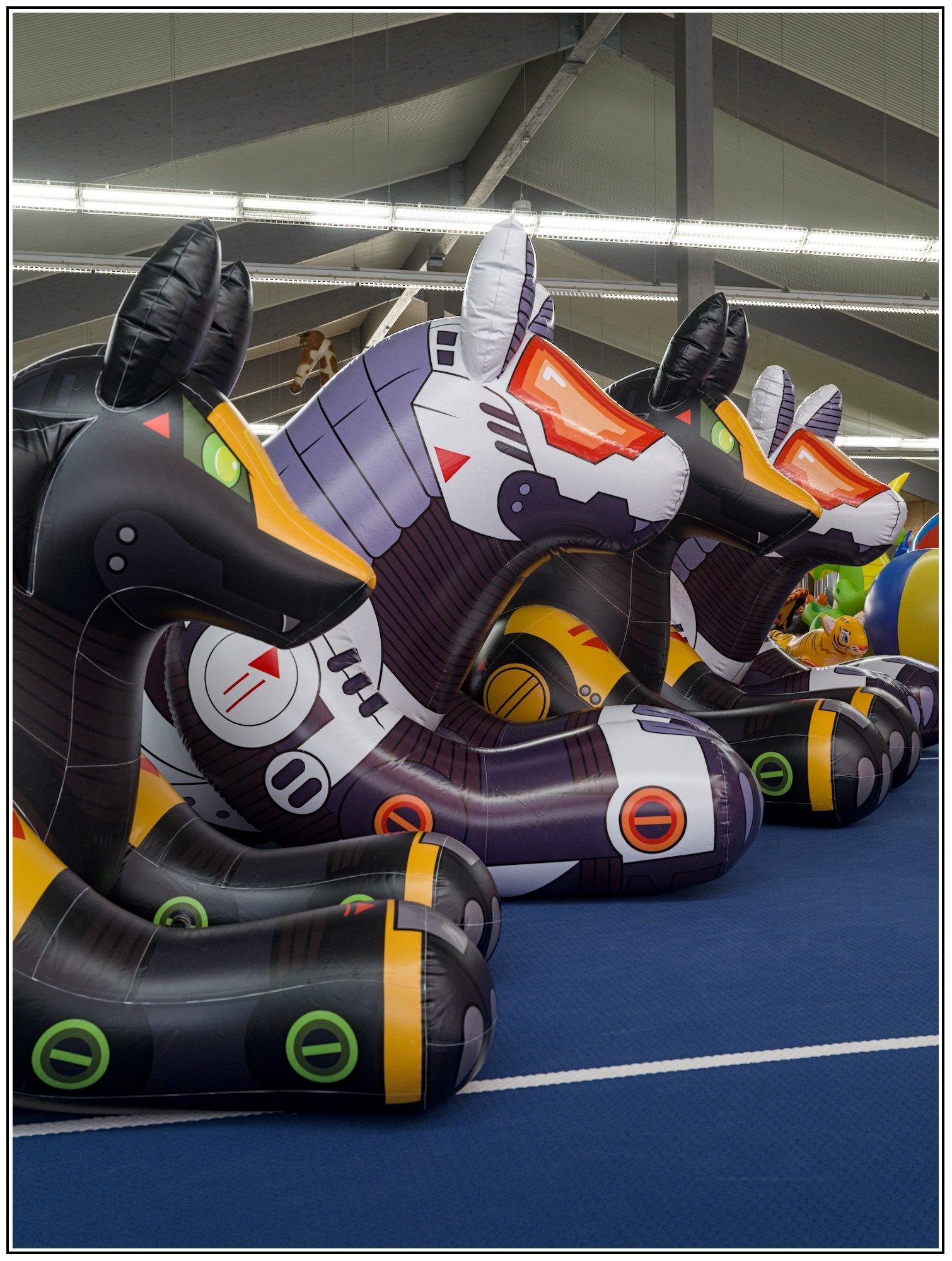 A row of different size inflatable mecha beast sorted from smallest to largest interleaving black fox mecha with white wolf mecha, taken from an dutch angle-ish perspective